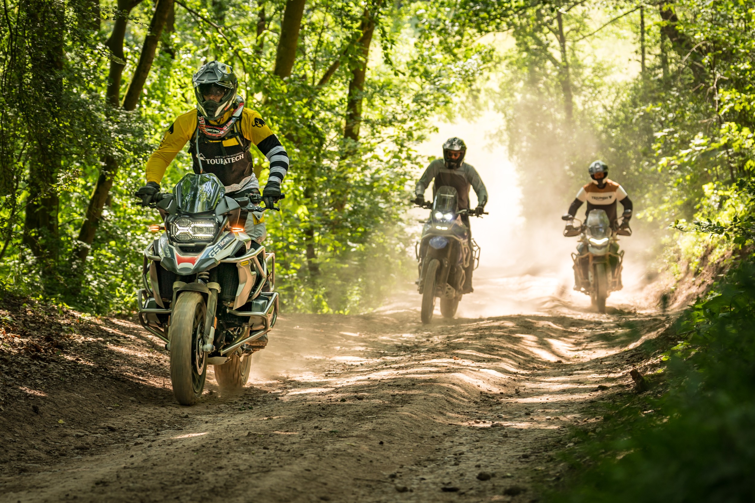 Drei Adventure-Biker auf einem Waldweg im Gelände